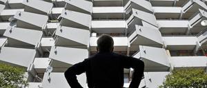 Ein Junge vor einem Wohnhochhaus mit Balkonen und Satellitenschüsseln.