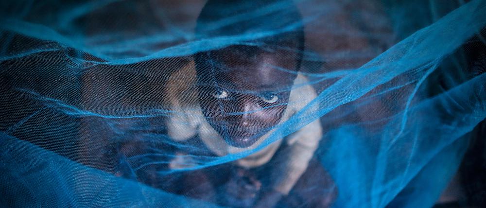 Ein Kind aus Burundi unter einem Moskitonetz