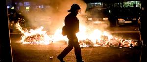 Ein Polizist geht an einem Feuer auf einer Straße am Rande der Demonstration linker und linksradikaler Gruppen unter dem Motto „Demonstration zum revolutionären 1. Mai“ vorbei.