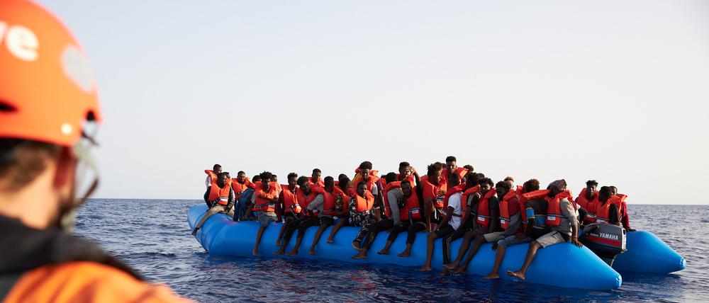Ein Seenotretter schaut zu einem Flüchtlingsboot.