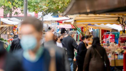 Menschen tragen Mund-Nasen-Bedeckungen und gehen in Berlin-Kreuzberg über den Markt am Maybachufer (Symbolbild).