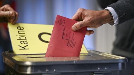 04.01.2023, Berlin: Zum Beginn der Briefwahl für die Wiederholungswahlen am 12. Februar wählt ein Mann im Rathaus Zehlendorf und steckt seine Stimmzettel in einem Briefumschlag für die Briefwahl in die Wahlurne. Foto: Jens Kalaene/dpa +++ dpa-Bildfunk +++