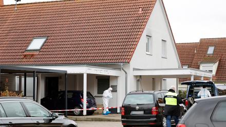  Polizisten und Mitarbeiter der Spurensicherung stehen vor einem Haus.