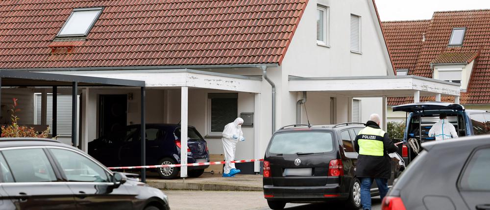  Polizisten und Mitarbeiter der Spurensicherung stehen vor einem Haus.