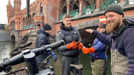 Die Aktiven von Spree:publik bei einer Cleanup Aktion an der Oberbaumbrücke. Mit Bootshaken fischen sie E-Scooter und Leihräder aus dem Wasser.