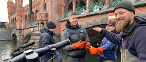 Die Aktiven von Spree:publik bei einer Cleanup Aktion an der Oberbaumbrücke. Mit Bootshaken fischen sie E-Scooter und Leihräder aus dem Wasser.
