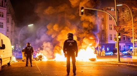 Polizei schützt Feuerwehr: Beamte sichern in der Silvesternacht Feuerwehrleute ab, die eine brennende Barrikade in Kreuzberg löschen. (Archivfoto)