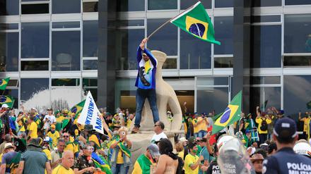 Anhänger des ehemaligen brasilianischen Präsidenten Bolsonaro stehen auf dem Dach des Kongressgebäudes in Brasilia. 