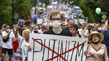 Ein Mann mit Mundschutz hält ein Plakat mit der durchgestrichenen Aufschrift „Putinizm“ (Putinismus) bei einem Protest zur Unterstützung von Sergej Furgal, dem Gouverneur der Region Chabarowsk, in der Hand.