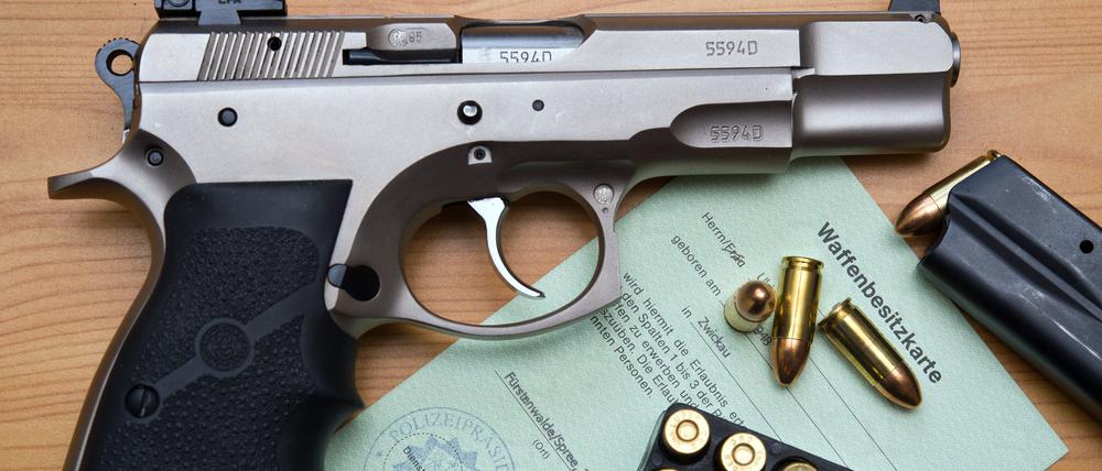 Eine Kaliber 9 mm Pistole, Patronen und ein Magazin liegen auf einer Waffenbesitzkarte.
