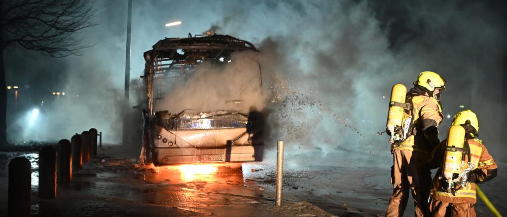 Feuerwehrleute löschen an der Neuköllner Sonnenallee einen Reisebus, der von Unbekannten angezündet worden war.