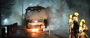 Feuerwehrleute löschen an der Neuköllner Sonnenallee einen Reisebus, der von Unbekannten angezündet worden war.