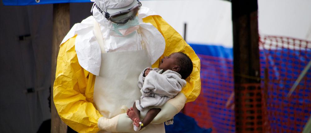 Ein möglicherweise mit Ebola infiziertes, zwei Wochen altes Kind wird im Osten von Guinea in einem Behandlungszentrum von einem Arzt auf dem Arm gehalten.