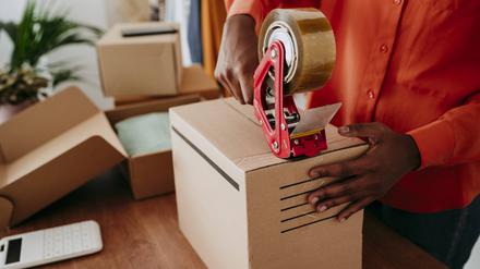 Hands of businesswoman sealing packages with tape at desk model released, Symbolfoto property released, EBBF06846