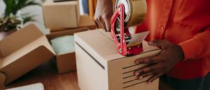 Hands of businesswoman sealing packages with tape at desk model released, Symbolfoto property released, EBBF06846