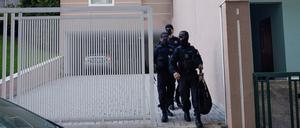 Polizisten kommen nach dem Haftbefehl aus dem Haus des Sicherheitschefs.