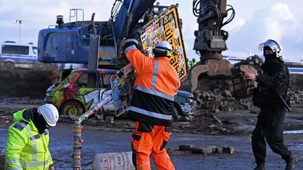 RWE-Mitarbeiter entfernen das Ortsschild des Dorfes Lützerath.