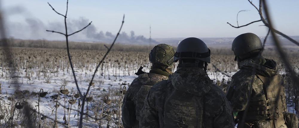 Ukrainische Soldaten blicken während der Kämpfe zwischen ukrainischen und russischen Truppen auf aufsteigende Rauchwolken. Der Kreml hat die Einnahme der Stadt Soledar in der Ostukraine nicht offiziell bestätigt, aber von einer „positiven Dynamik“ gesprochen.