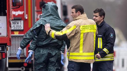 Spezialkräfte der Feuerwehr in Schutzanzügen kommen von ihrem Einsatz.