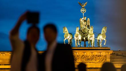 Besucher machen am Abend vor dem Brandenburger Tor ein Selfie. 