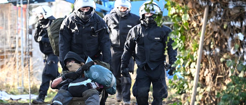 Polizisten schieben einen Klimaaktivisten mit der Schubkarre vom Gelände in Lützerath. Der Energiekonzern RWE will die unter Lützerath liegende Kohle abbaggern.