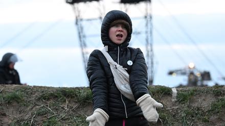 Die Klimaaktivistin Greta Thunberg (r) steht zwischen Keyenberg und Lützerath unter Polizeibewachung am Rande des Tagebaus und tanzt. 