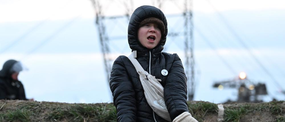 Die Klimaaktivistin Greta Thunberg (r) steht zwischen Keyenberg und Lützerath unter Polizeibewachung am Rande des Tagebaus und tanzt.