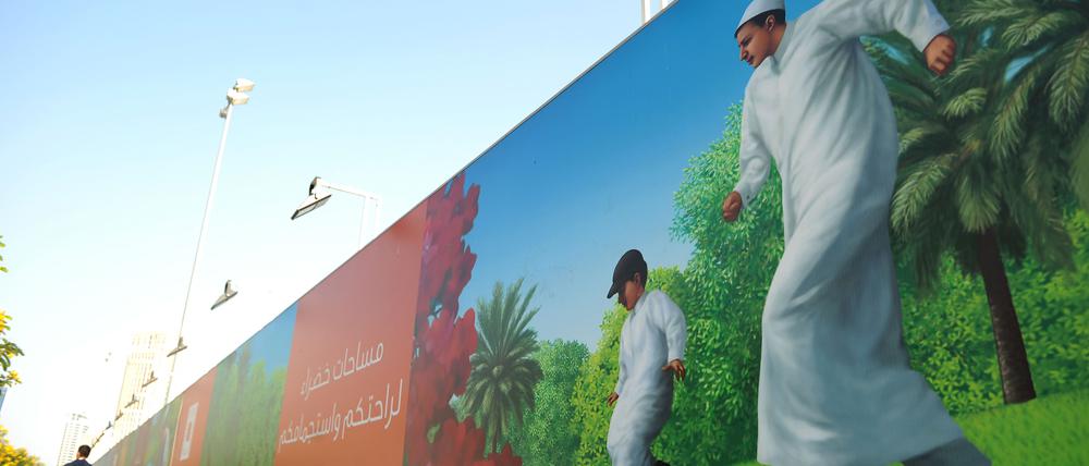 Ein Passant geht in Doha an einem Plakat vorbei, auf dem Einheimische Fussball spielen.