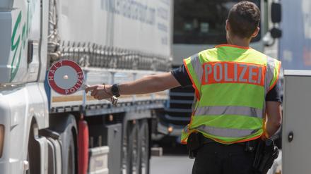  Ein Polizist steht mit einer Kelle an einer Kontrollstelle der Bundespolizei auf der Autobahn 3 kurz hinter der deutsch-österreichischen Grenze. (Archivbild)