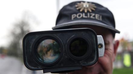 Ein Polizeibeamter misst mit einer Radarmesspistole die Geschwindigkeit von Fahrzeugen. 
