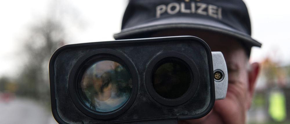 Ein Polizeibeamter misst mit einer Radarmesspistole die Geschwindigkeit von Fahrzeugen.