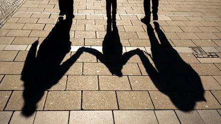 ARCHIV - 04.04.2022, Bayern, München: Die Schatten von zwei Erwachsenen und einem Kind fallen in den Morgenstunden auf den Asphalt.Die Einführung einer sogenannten Kindergrundsicherung gehört zu den zentralen sozialpolitischen Vorhaben der Ampelkoalition. Nun hat Bundesfamilienministerin Paus (Grüne) dafür Eckpunkte vorgelegt. Ein Ministeriumssprecher bestätigte am Donnerstag, dass ein entsprechendes Papier an die anderen Ministerien zur weiteren Abstimmung verschickt wurde. Foto: Peter Kneffel/dpa +++ dpa-Bildfunk +++