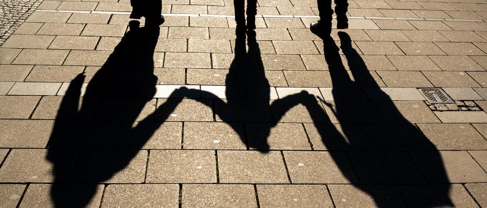 ARCHIV - 04.04.2022, Bayern, München: Die Schatten von zwei Erwachsenen und einem Kind fallen in den Morgenstunden auf den Asphalt.Die Einführung einer sogenannten Kindergrundsicherung gehört zu den zentralen sozialpolitischen Vorhaben der Ampelkoalition. Nun hat Bundesfamilienministerin Paus (Grüne) dafür Eckpunkte vorgelegt. Ein Ministeriumssprecher bestätigte am Donnerstag, dass ein entsprechendes Papier an die anderen Ministerien zur weiteren Abstimmung verschickt wurde. Foto: Peter Kneffel/dpa +++ dpa-Bildfunk +++