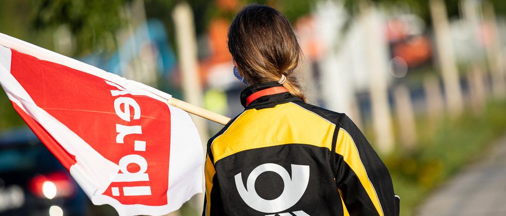 Eine Beschäftigte der Deutschen Post steht mit einer Fahne der Gewerkschaft Verdi vor der Deutsche-Post-DHL-Niederlassung im Stadtteil Anderten.