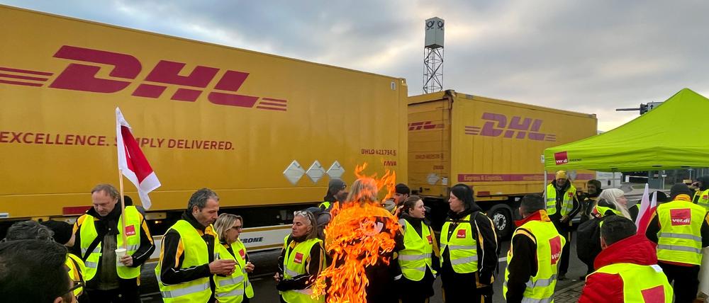 In Köln stehen streikende Mitarbeitende der Post vor einem LKW.