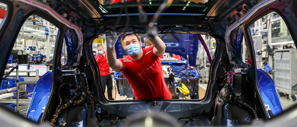 Ein Mitarbeiter von Porsche arbeitet mit Mundschutz in der Montage an einem Macan