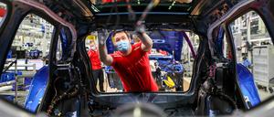 Ein Mitarbeiter von Porsche arbeitet mit Mundschutz in der Montage an einem Macan