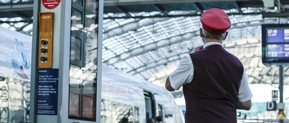 Ein Zugbegleiter gibt ein Abfahrtszeichen für einen ICE auf dem Bahnsteig im Berliner Hauptbahnhof.