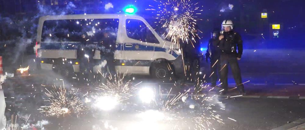 Polizeibeamte stehen hinter explodierendem Feuerwerk. An Silvester kam es in Berlin zu heftigen Ausschreitungen. (Archivbild)