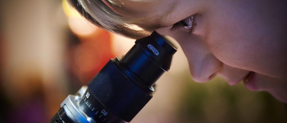 Portrait of Child Boy looking through microscope in school laboratory