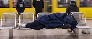 Ein Obdachloser schläft auf einer Bank am Bahnhof Alexanderplatz in Berlin-