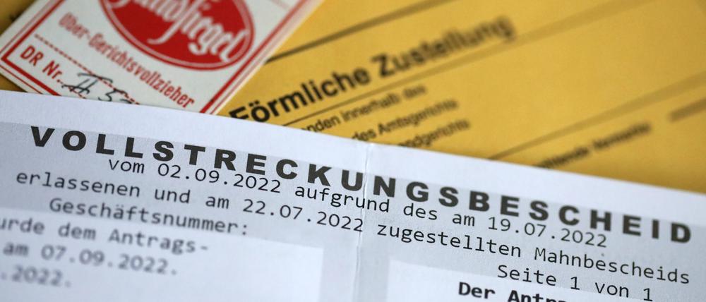 Pfandsiegel eines Gerichtsvollziehers neben einem Vollstreckungsbescheid (Symbolbild).