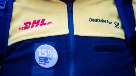 Eine Teilnehmerin eines Streiks von Post-Beschäftigten trägt vor dem Sitz des Verdi Landesbezirks Berlin-Brandenburg Dienstkleidung und einen 15%-Anstecker. 
