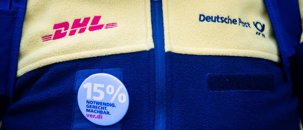 Eine Teilnehmerin eines Streiks von Post-Beschäftigten trägt vor dem Sitz des Verdi Landesbezirks Berlin-Brandenburg Dienstkleidung und einen 15%-Anstecker. 