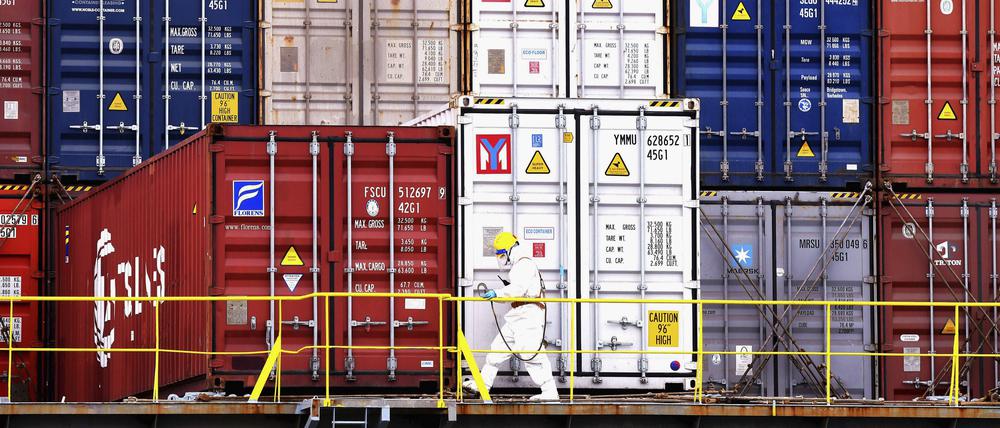  Ein Arbeiter in Schutzkleidung arbeitet in der Nähe von Containern auf einem Schiff in Qingdao in der ostchinesischen Provinz Shandong.