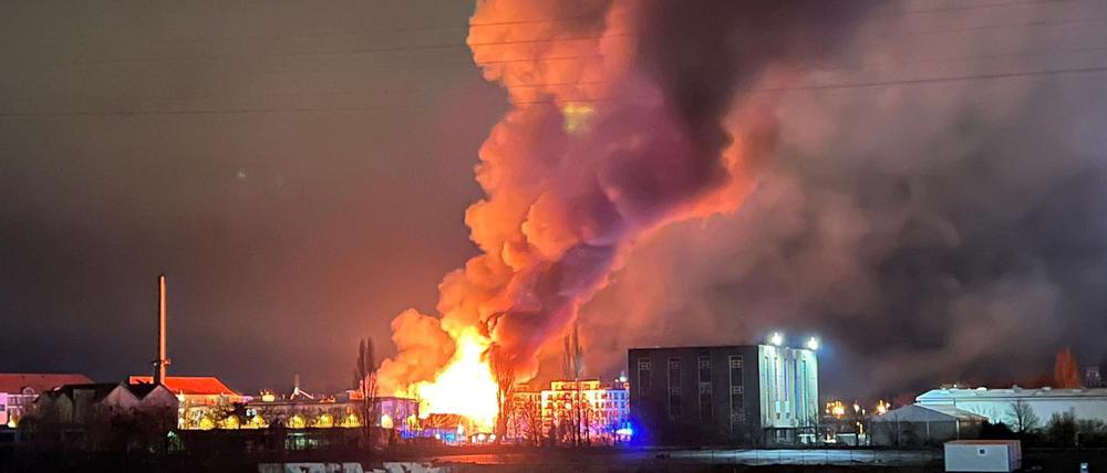 28.01.2023, Berlin: Flammen schlagen hoch in den Nachthimmel über Berlin. Ein Feuer in einer Lagerhalle im Berliner Ortsteil Oberschöneweide hat am frühen Samstagmorgen ein Großaufgebot von über 100 Einsatzkräften auf den Plan gerufen. Beim Eintreffen der Feuerwehr stellte sich heraus, dass die Lagerhalle eines Parkettherstellers in voller Ausdehnung brannte. Foto: Julius-Christian Schreiner/dpa +++ dpa-Bildfunk +++