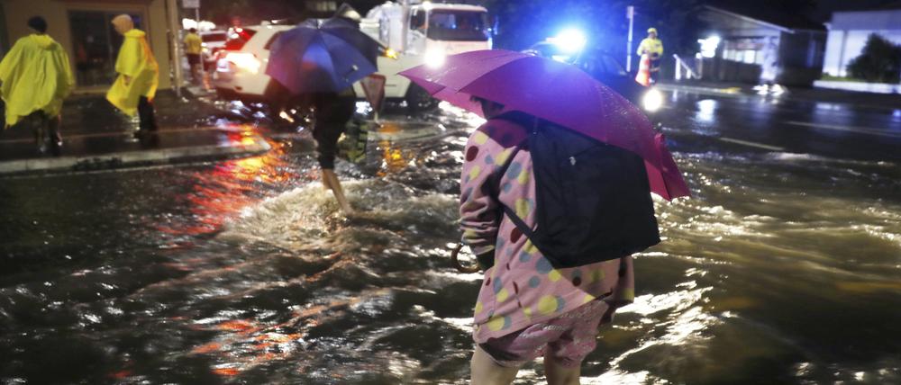 Menschen überqueren nach massiven Regenfällen eine überflutete Straße in Auckland, Neuseeland.