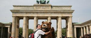 Touristen fotografieren sich mit einem Berliner Bären am Brandenburger Tor in Berlin-Mitte.