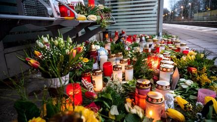 Kerzen und Blumen stehen und liegen im Bahnhof Brokstedt in einem Wartehäuschen.