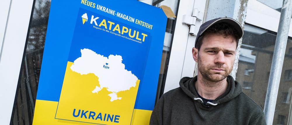 Der ehemalige Katapult-Geschäftsführer Benjamin Fredrich vor einem Poster des Ukraine-Magazins.